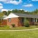 a brick house with a lawn and trees in the front